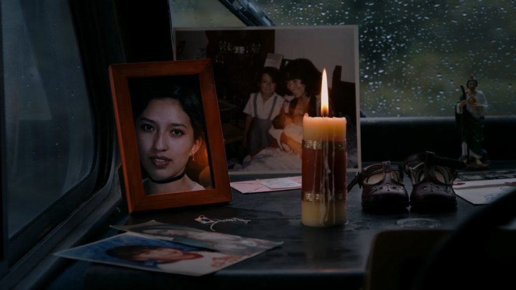 Auf einer Ablage am Fenster des Wohnwagens stehen mehrere Fotos von Monica, als Kind und als junge Frau, sowie eine brennende Kerze, ein paar Babyschuhe und eine Heiligenfigur.