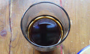 Ein Glas mit schwarzem Kaffee auf einem braunen Holztisch