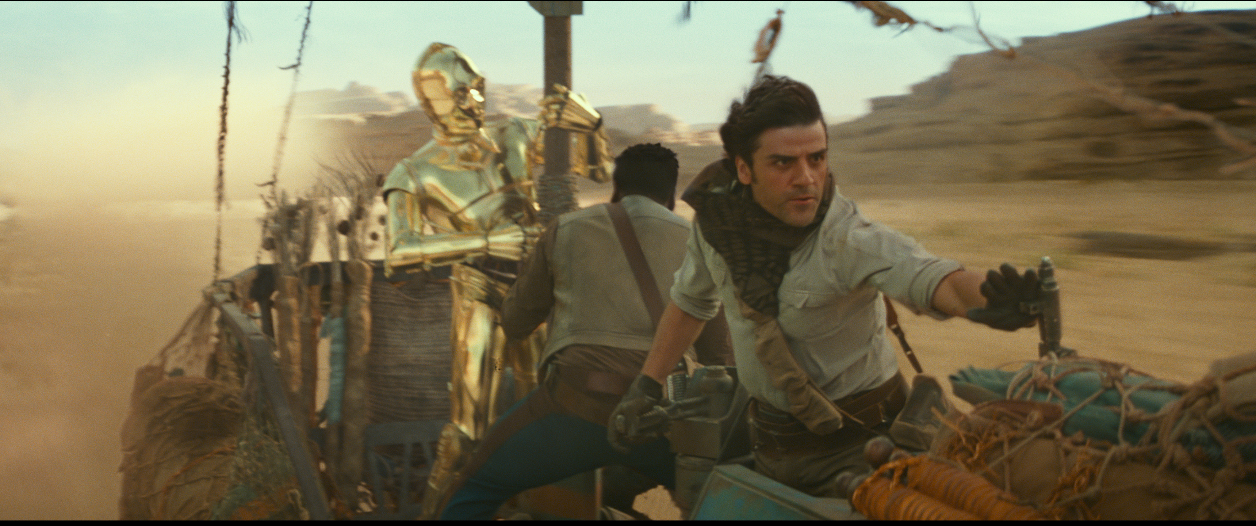 Die Filmfiguren Finn, gespielt von John Boyega, und Poe, gespielt von Oscar Isaac, mit C3PO auf einem Gefährt.