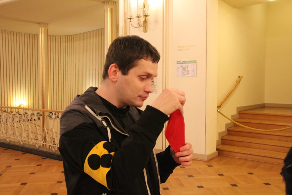 Dennis hält ein rotes Stück Stoff in den Händen und ertastet es.