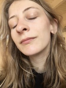 Das Bild zeigt die Kolumnistin Lisa auf einem Selfie. Die Sonne scheint ihr ins Gesicht, die hat die Augen geschlossen und den Kopf in leicht geneigt. 