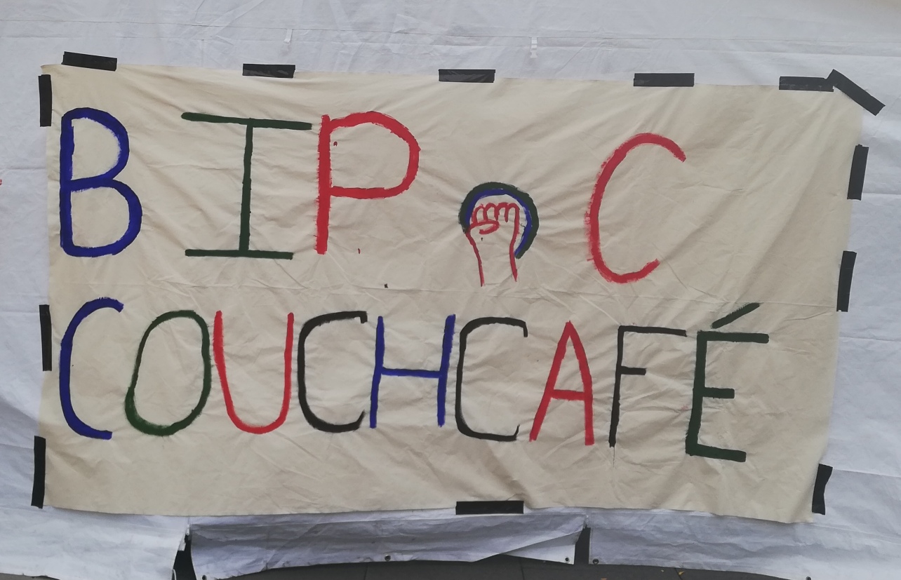 Zu sehen ist ein weißes Banner mit der Aufschrift "BIPoC Couchcafé" in bunten Buchstaben.