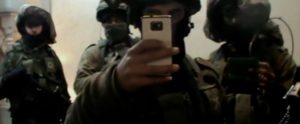 Einige uniformierte Soldaten filmen sich gegenseitig mit ihren Handys bei einer Durchsuchung. 