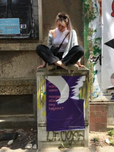 Leoni Habedank sitzt auf einem Stromkasten auf einem Gehweg.