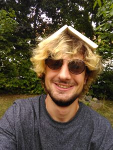 luhze-Autor Daniel mit Buch auf dem Kopf.