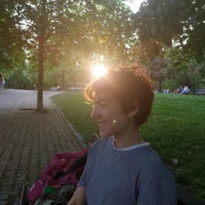 Kolumnist Eliah sitzt lächelnd auf einer Parkbank