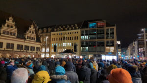 Der Leipziger Marktplatz ist mit Menschen gefüllt. Weiter hinten im Bild steht eine Bühne, auf der gerade Oberbürgermeister Jung spricht.